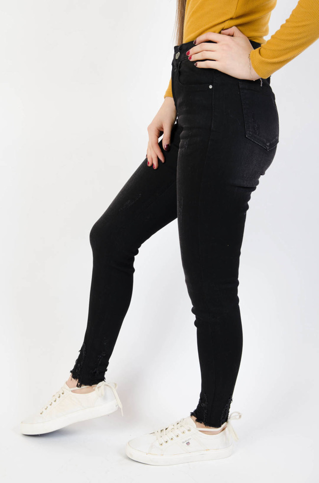 Czarne spodnie jeansowe z przetarciami i szarpaniami na nogawce