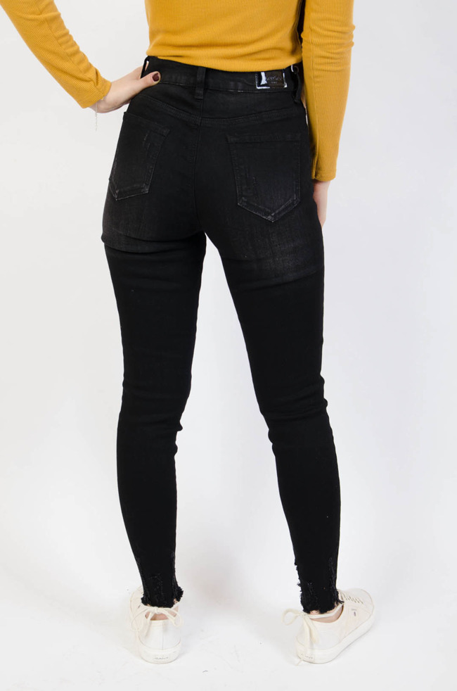 Czarne spodnie jeansowe z przetarciami i szarpaniami na nogawce