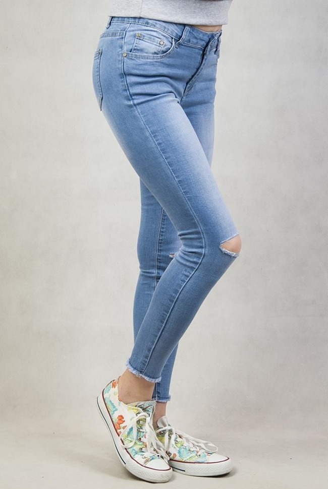 Spodnie jeansowe z dziurami na kolanach oraz frędzlami przy nogawkach