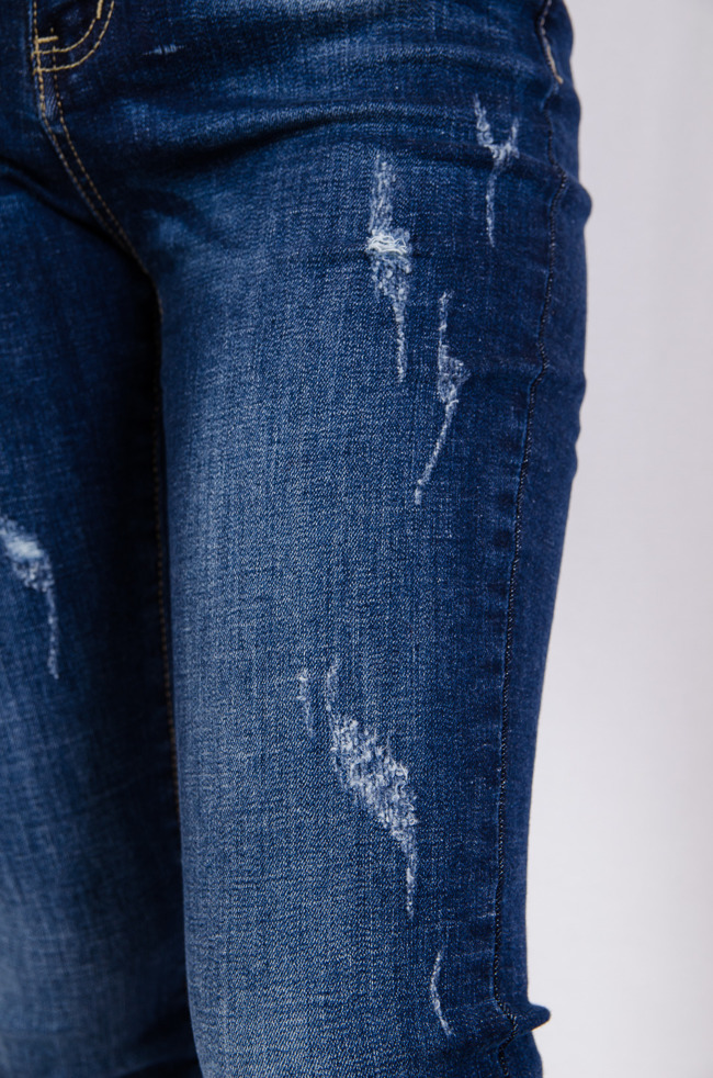 Spodnie jeansowe z licznymi przetarciami oraz naszywką na kieszeni